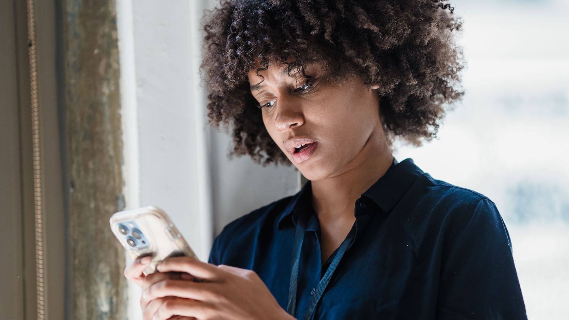 Young woman engaging with smartphone in modern office setting.