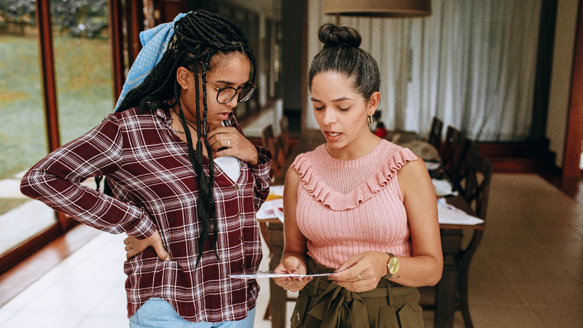 Two women engage in a discussion while examining a document in a well-lit room.