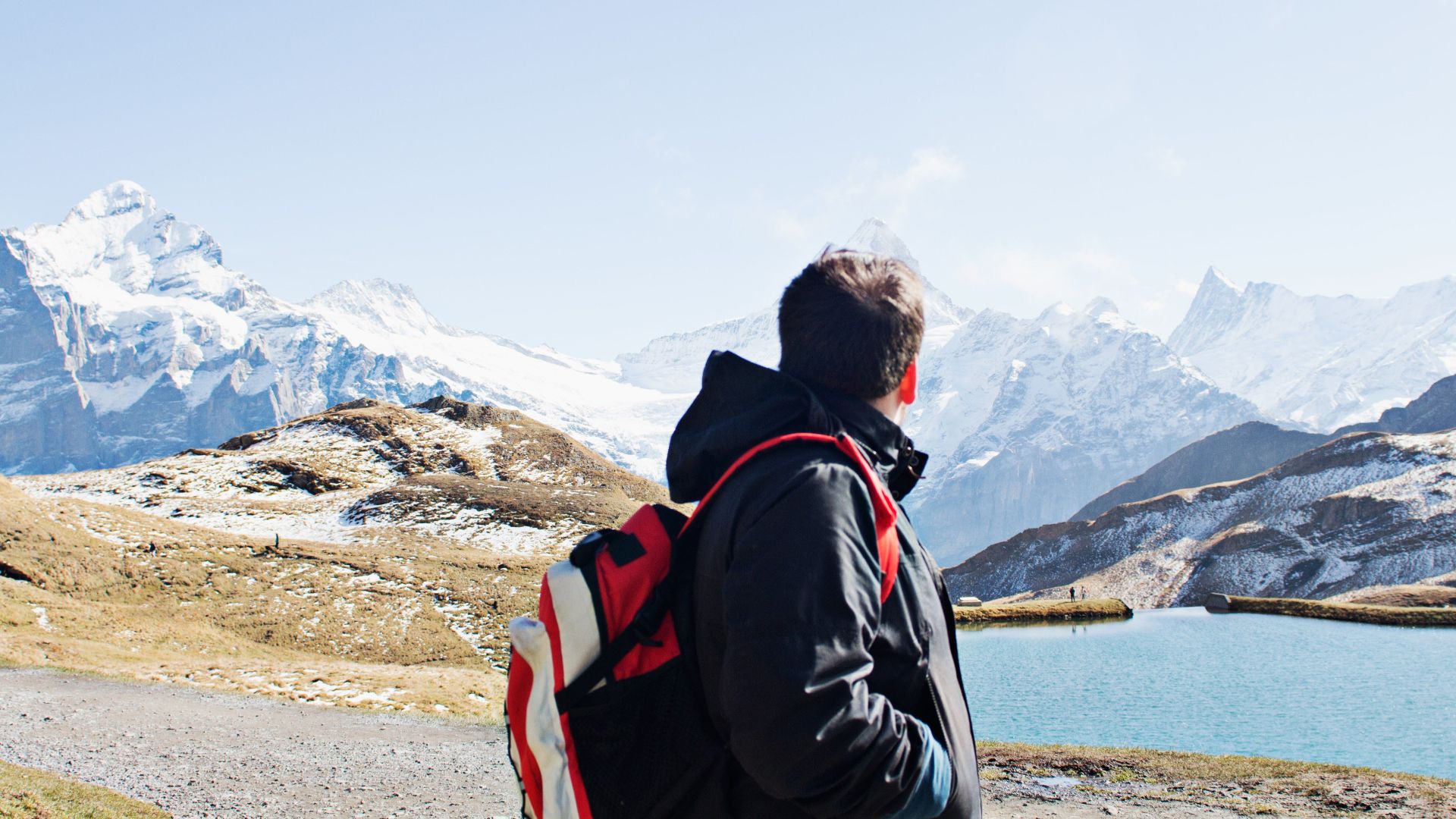 A hiker with a backpack exploring the stunning snowy landscapes of the Swiss Alps near Grindelwald.