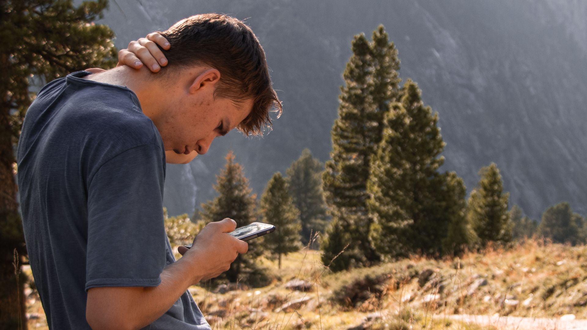 Young man relaxing with smartphone in Zillertal, Austria mountains.