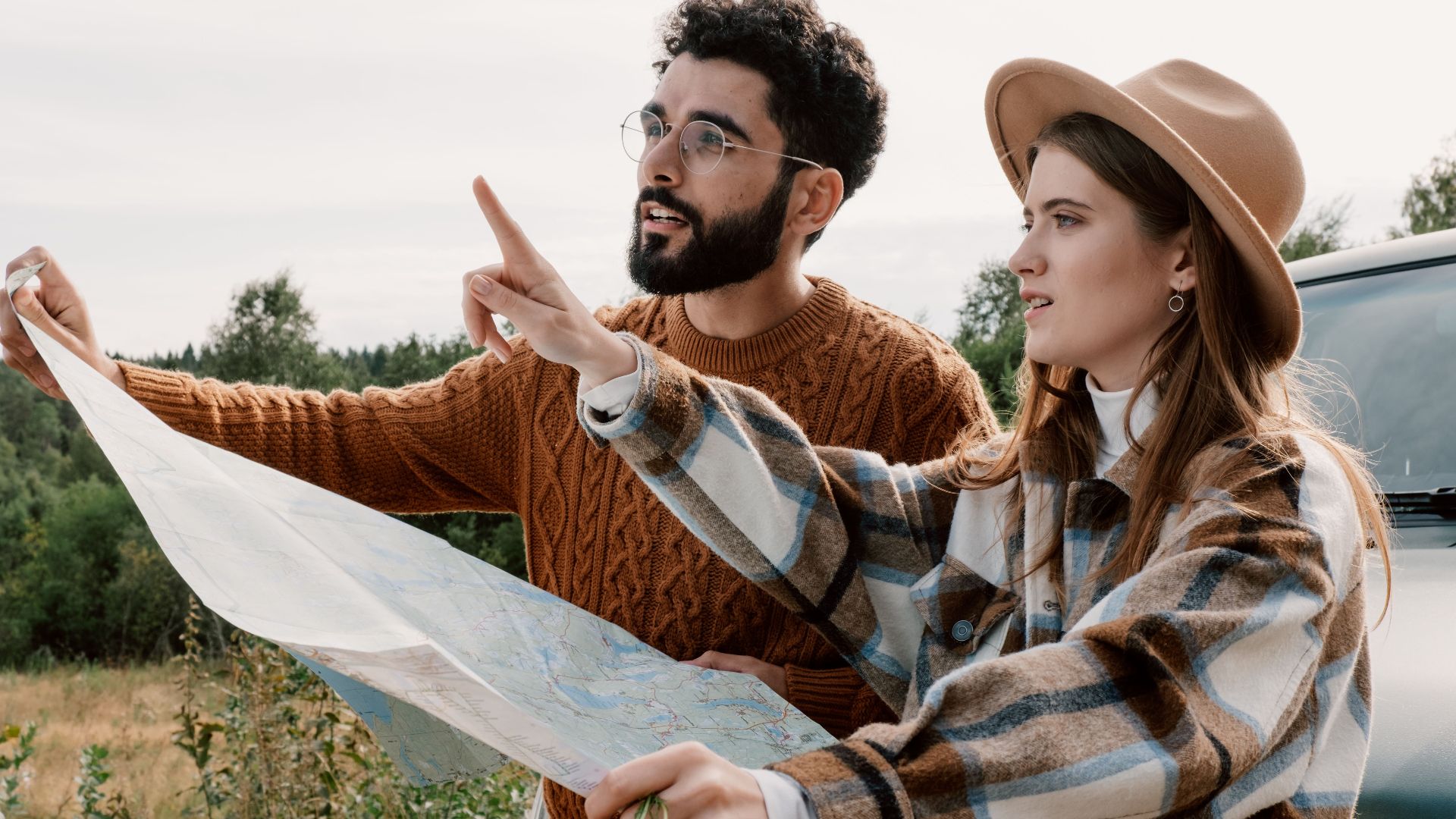A couple explores nature using a map during a road trip adventure.