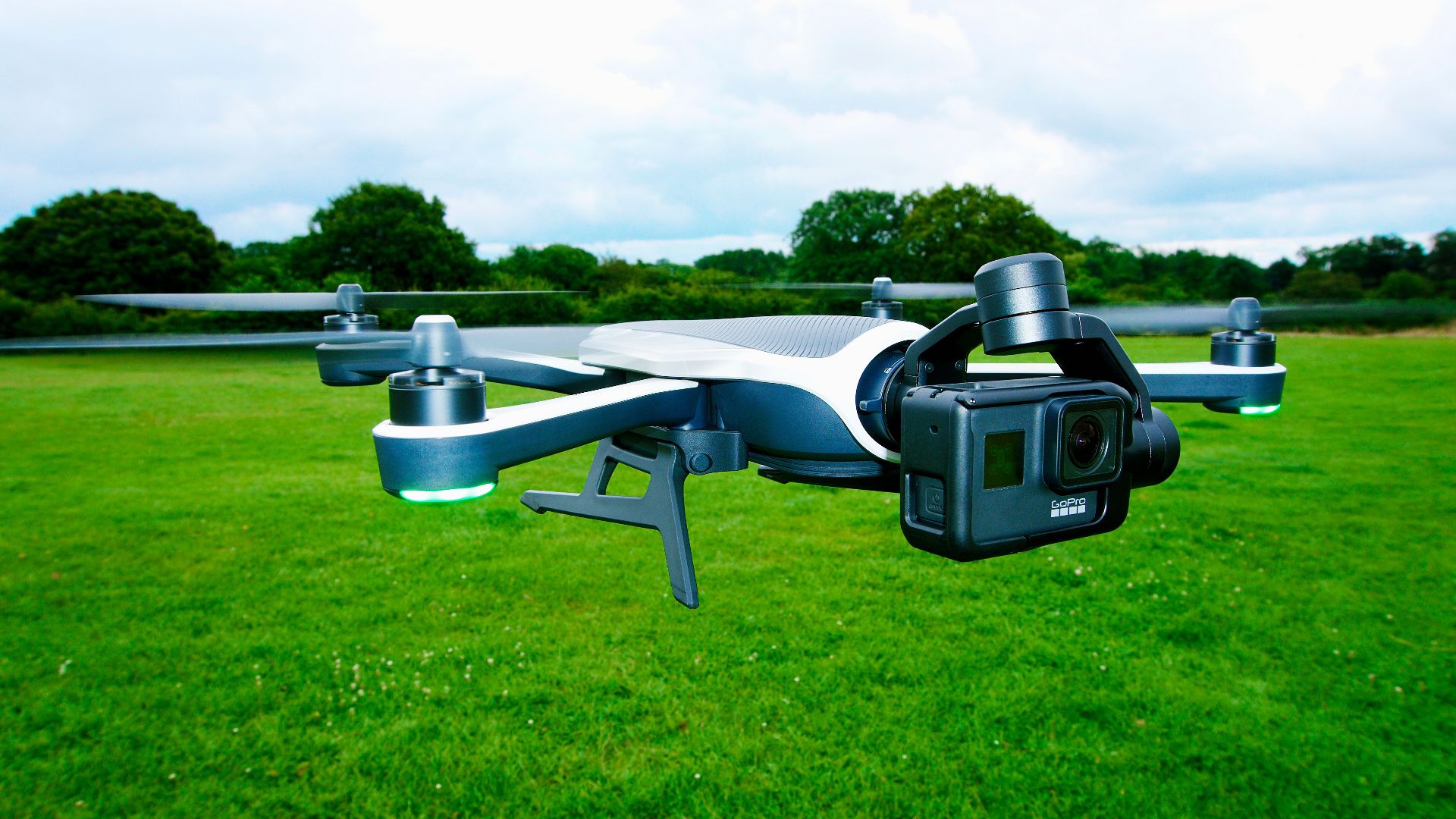 Close-up of a drone equipped with a camera flying over a vibrant green outdoor field.