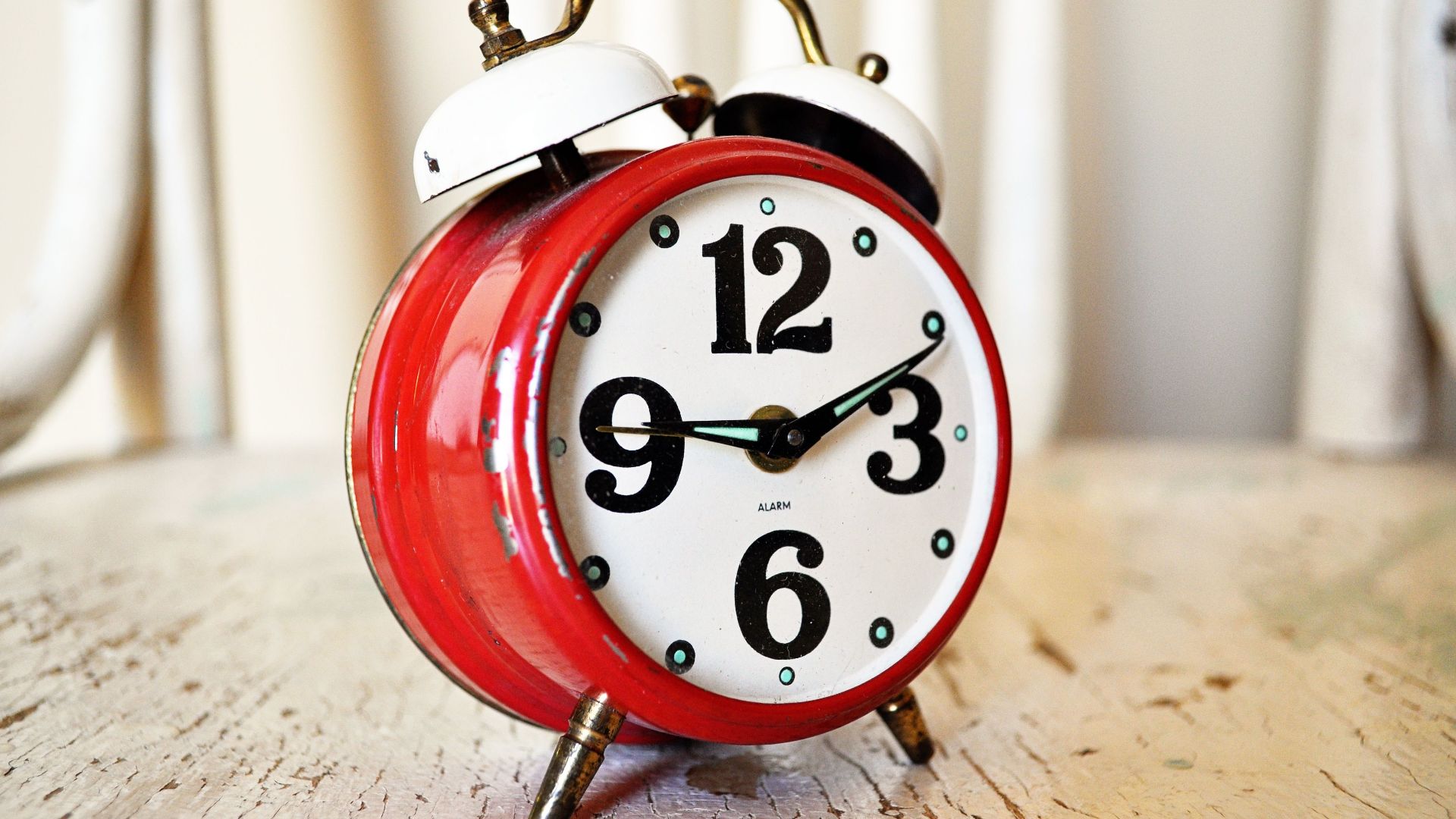 Close-up of vintage red alarm clock on rustic wood surface, indoors.
