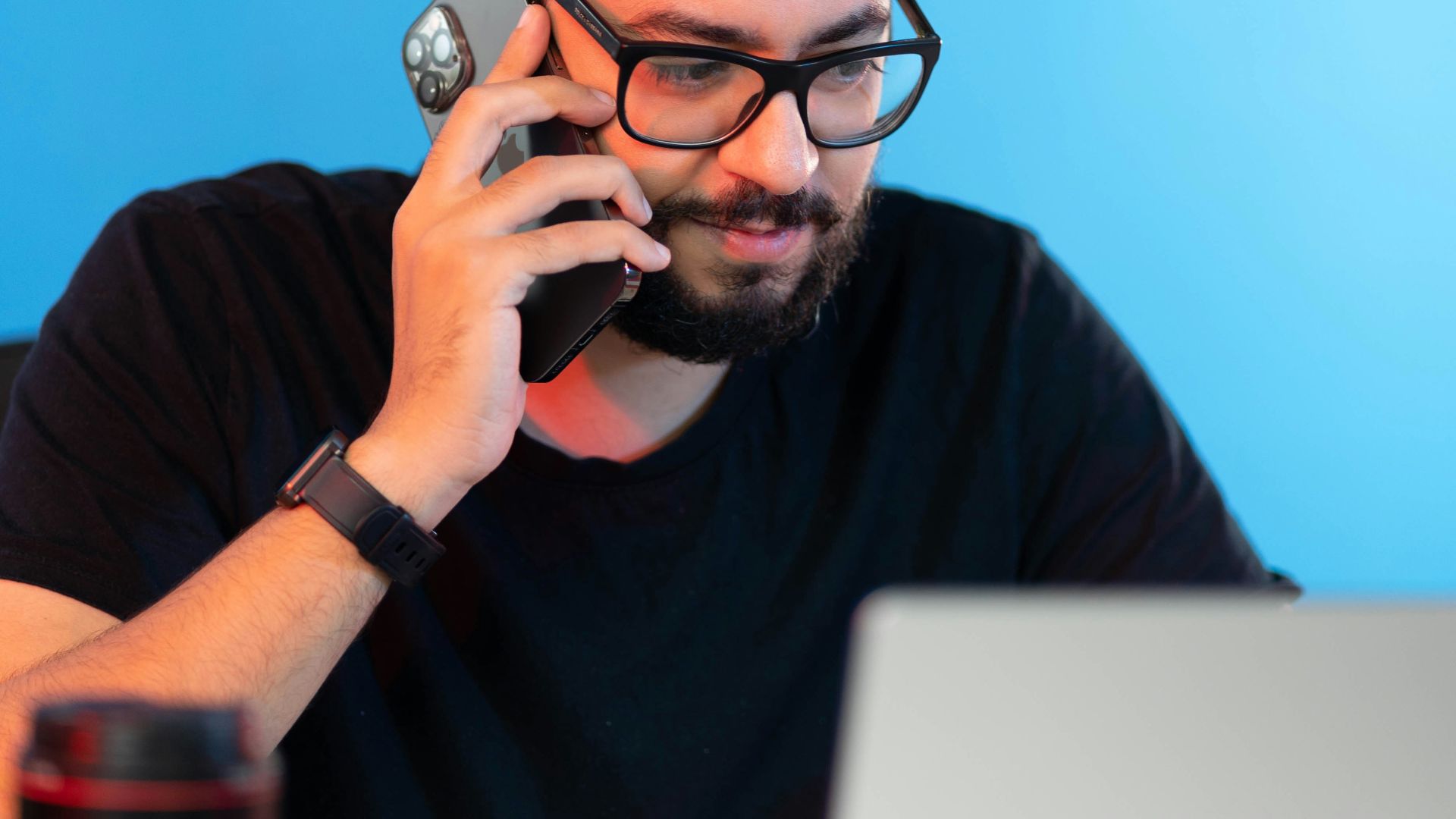 a man sitting at a desk talking on a cell phone
