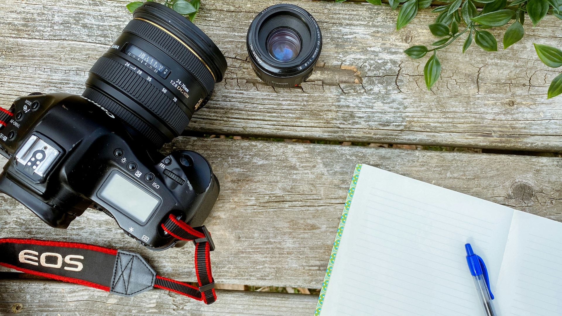 a camera and a notebook on a wooden table