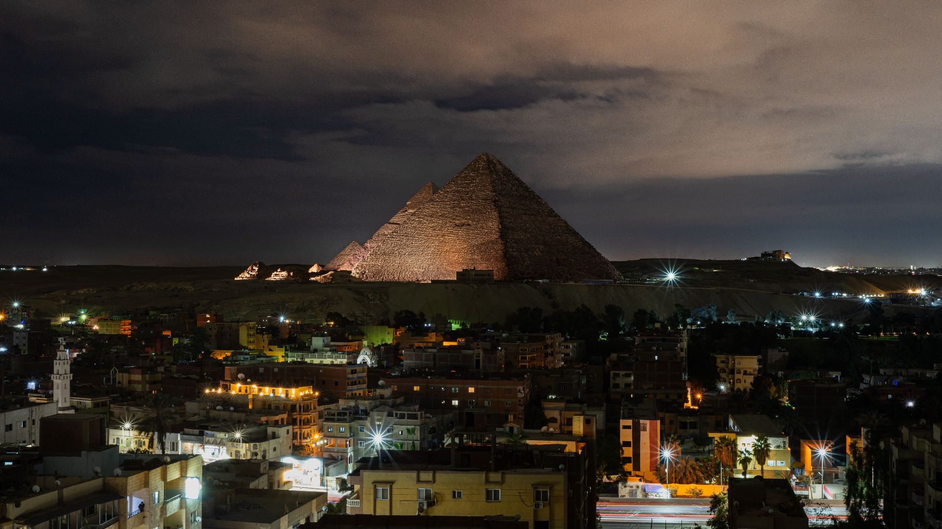 A stunning night view of the Giza Pyramids illuminated, capturing the vibrant cityscape of Giza, Egypt.