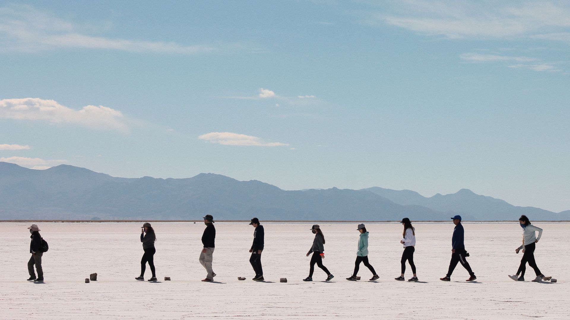 A group of people walking across the vast Salinas Grandes salt flats in Jujuy, Argentina.