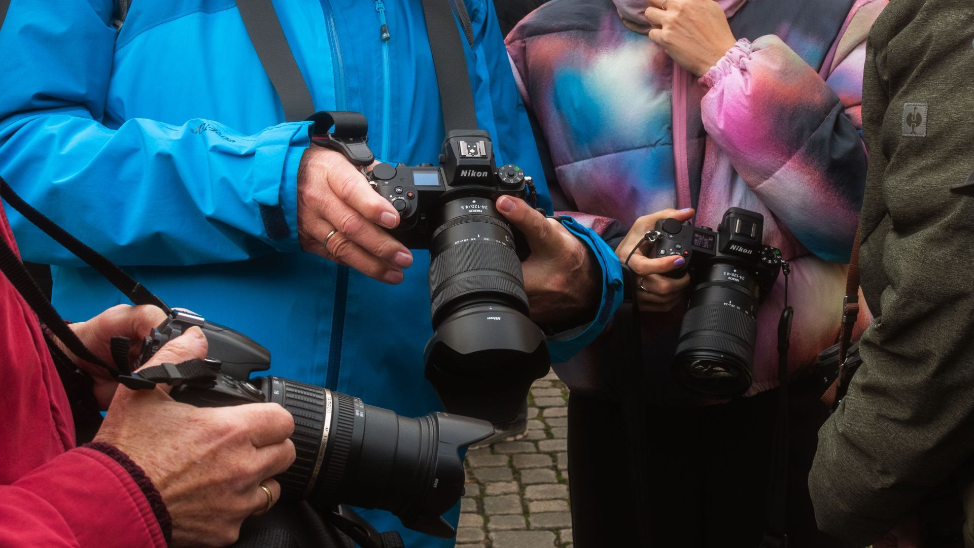 Photographers gathering and showcasing their advanced camera gear outdoors.