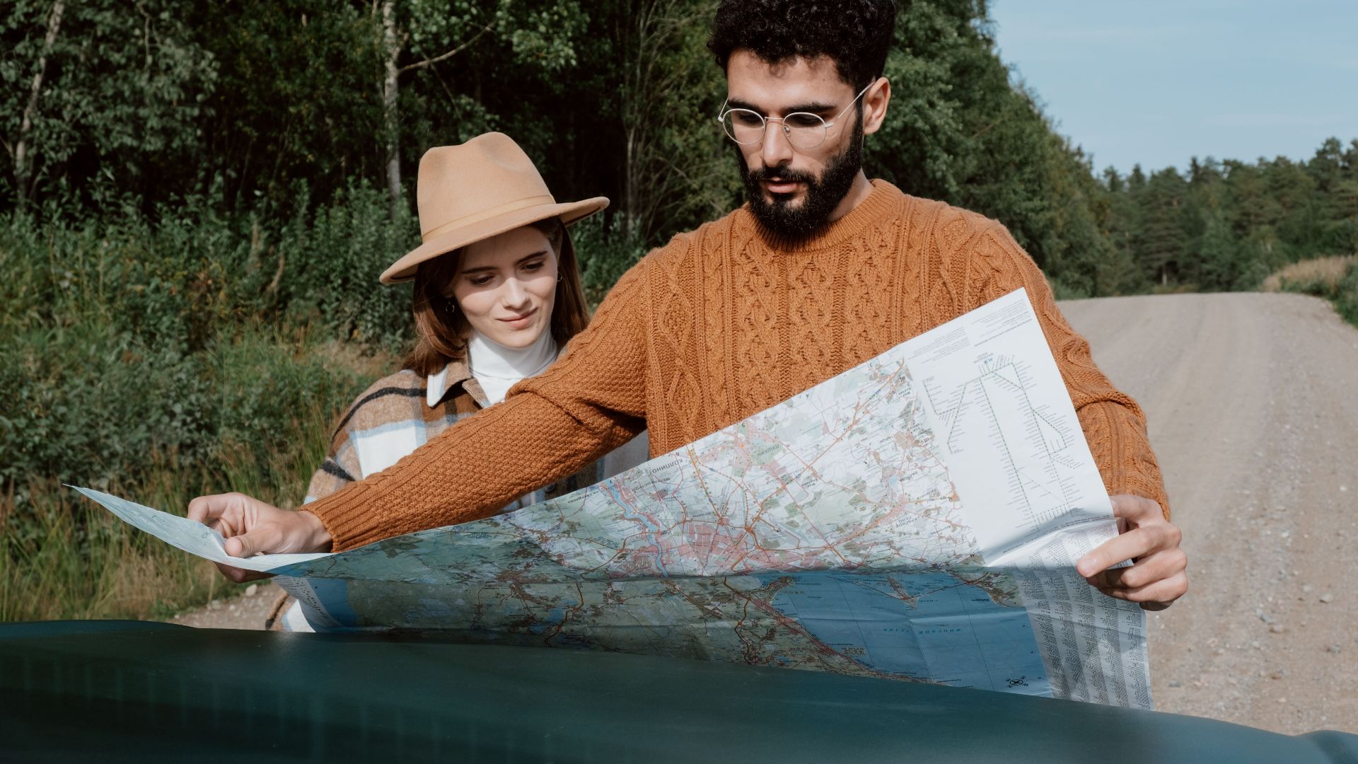 A young couple examines a map on a scenic outdoor road trip.