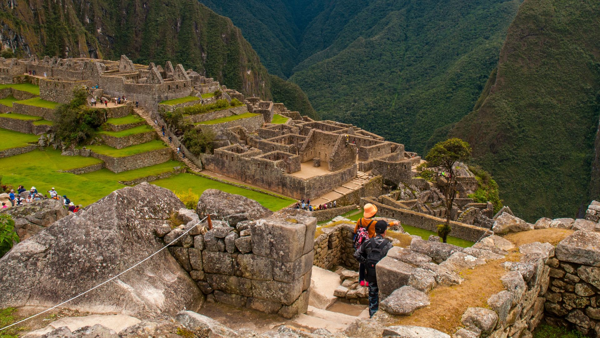 Breathtaking view of Machu Picchu amidst mountains, with tourists exploring the ancient Inca ruins.