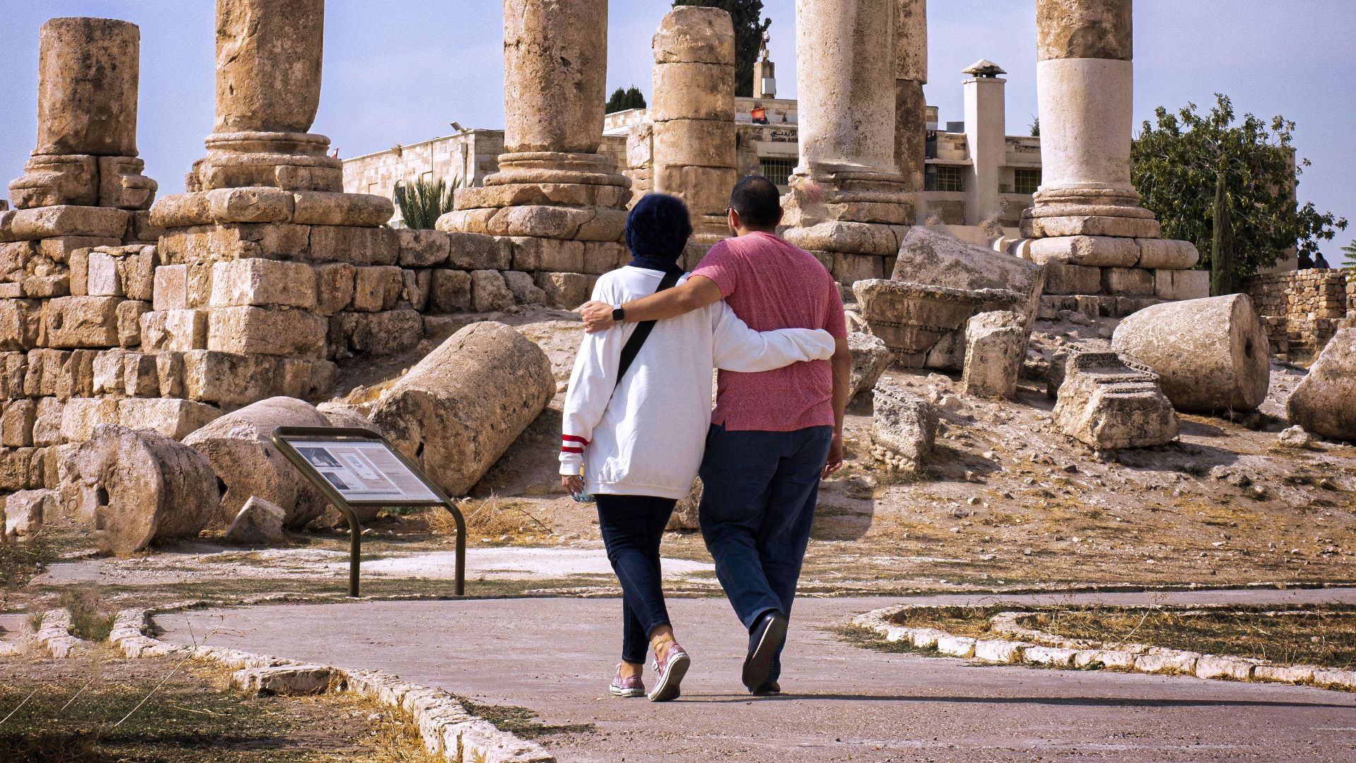 Couple explores the historic Amman Citadel with iconic pillars under a blue sky.