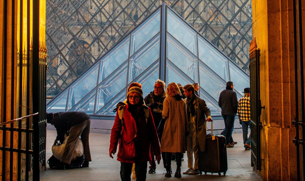 People enjoying a sunny day at the famous Louvre Pyramid in Paris, France