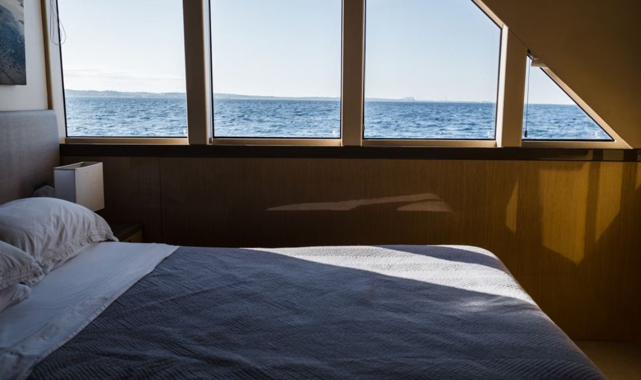 A serene bedroom interior featuring a wide ocean view through large windows