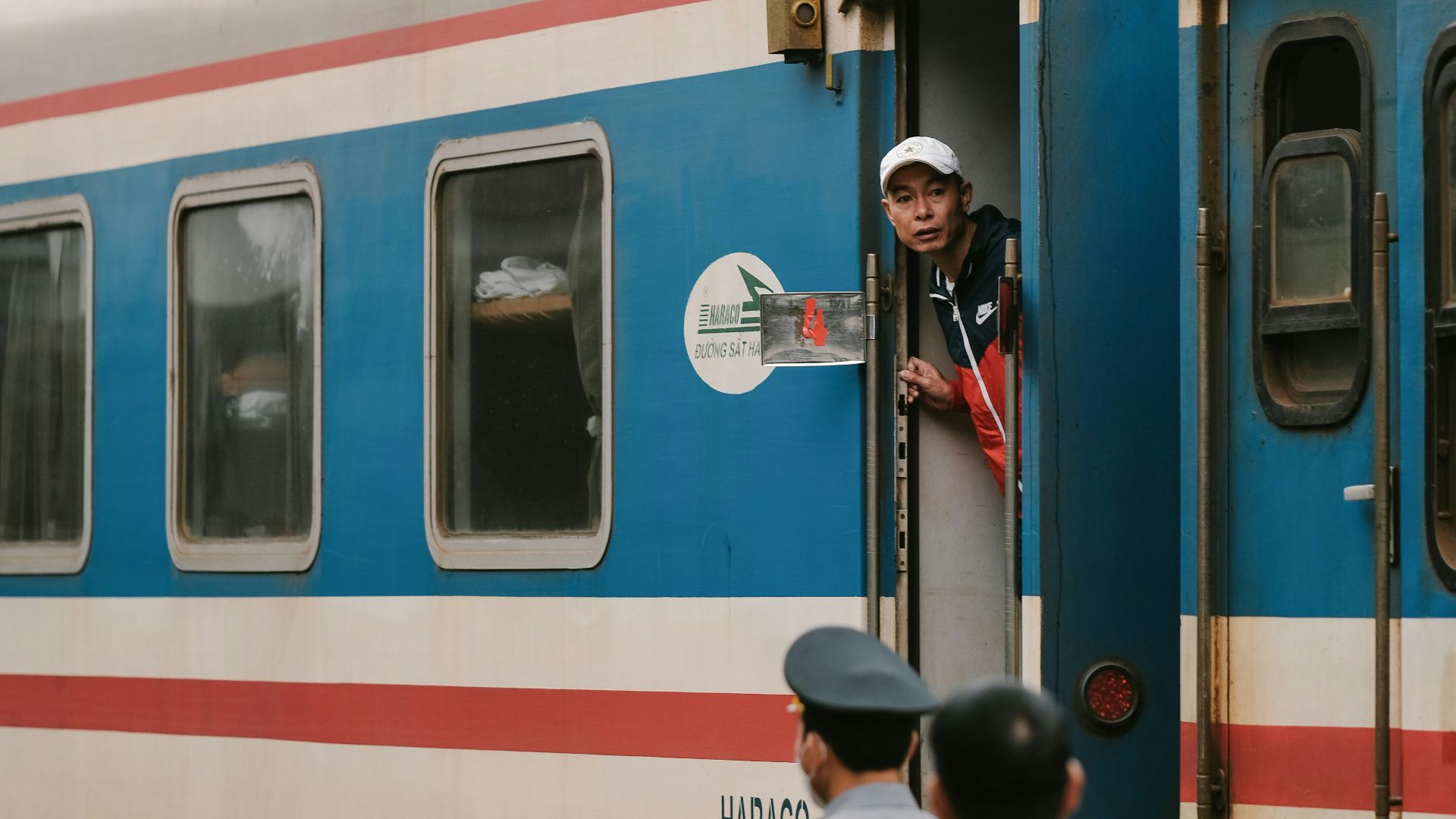 a man standing on the door of a blue and white train