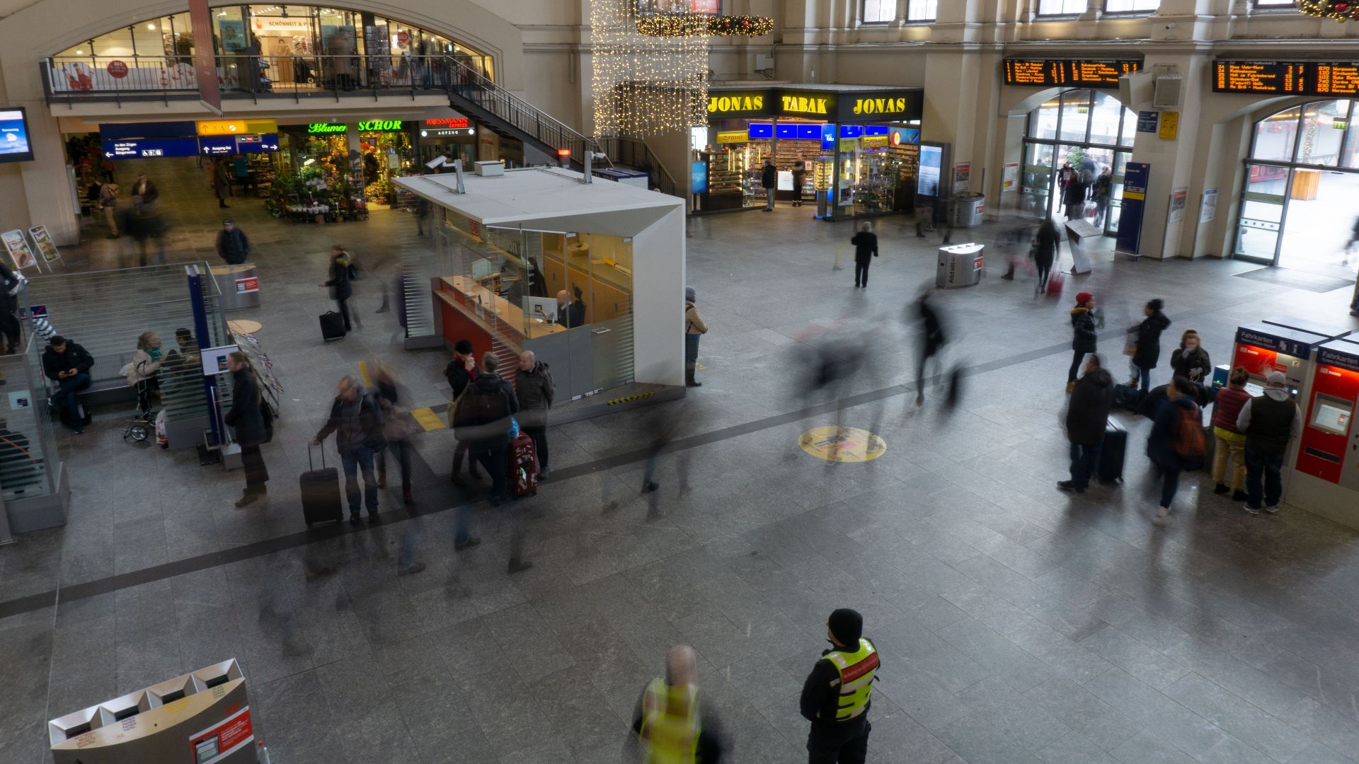 A bustling train station with blurred commuters, showcasing movement and travel.