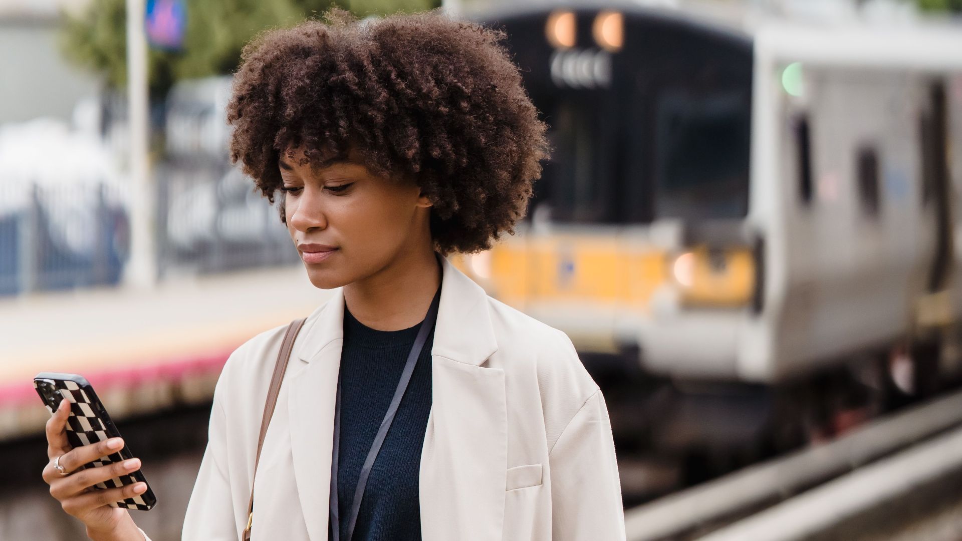 Young woman on train platform using smartphone, urban commute scene.