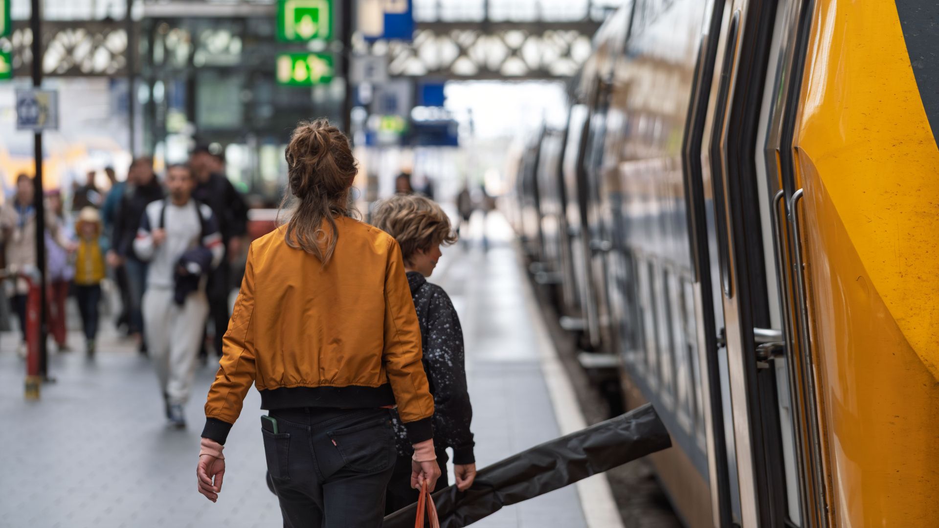 A woman and child boarding a train at a bustling station, capturing a moment of travel.