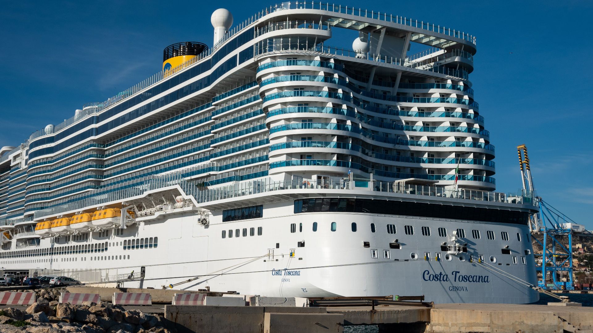 Costa Toscana cruise ship docked at a sunny harbor, showcasing modern luxury.