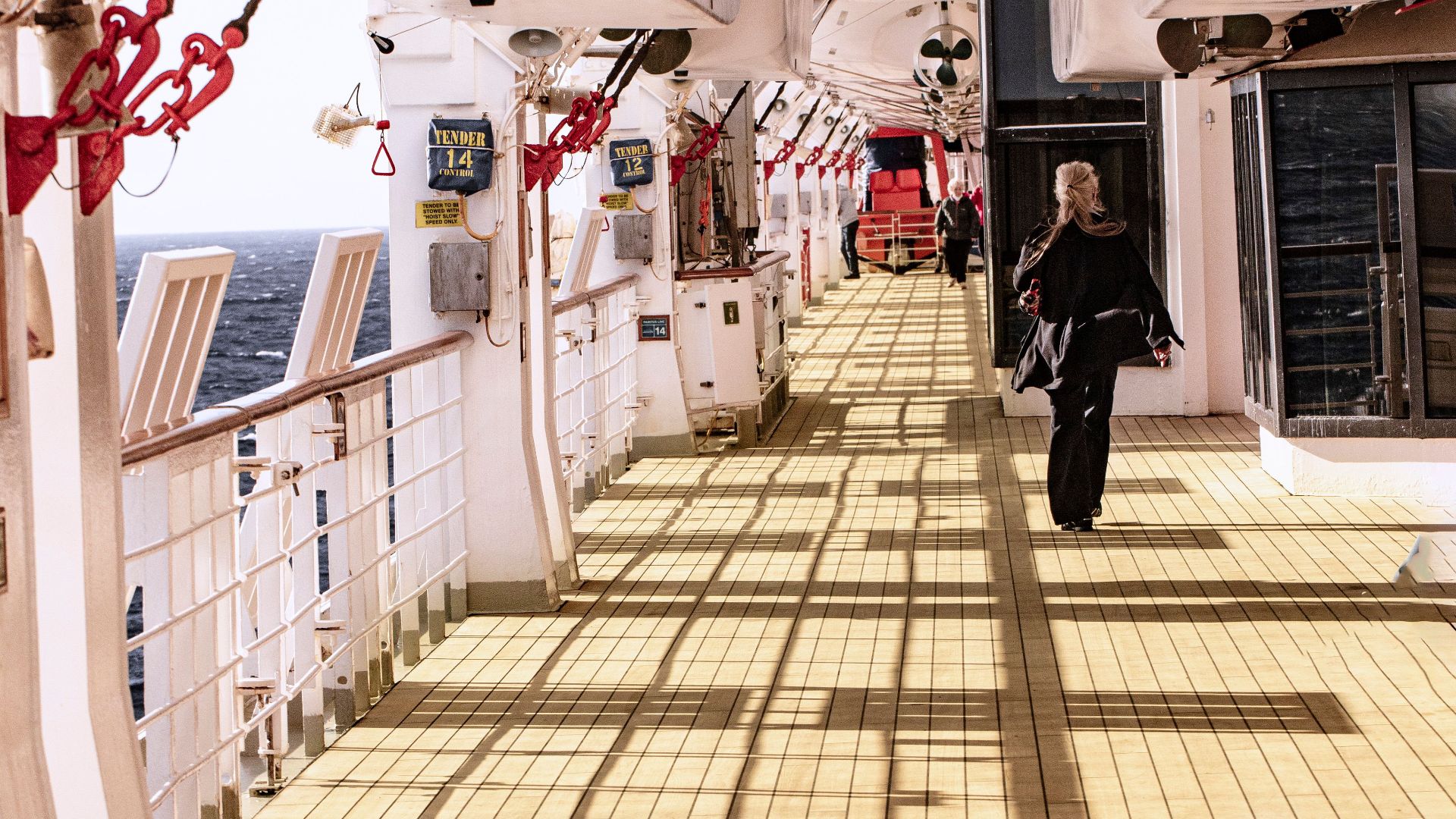 A serene moment captured on a cruise ship deck with a lone passenger strolling.