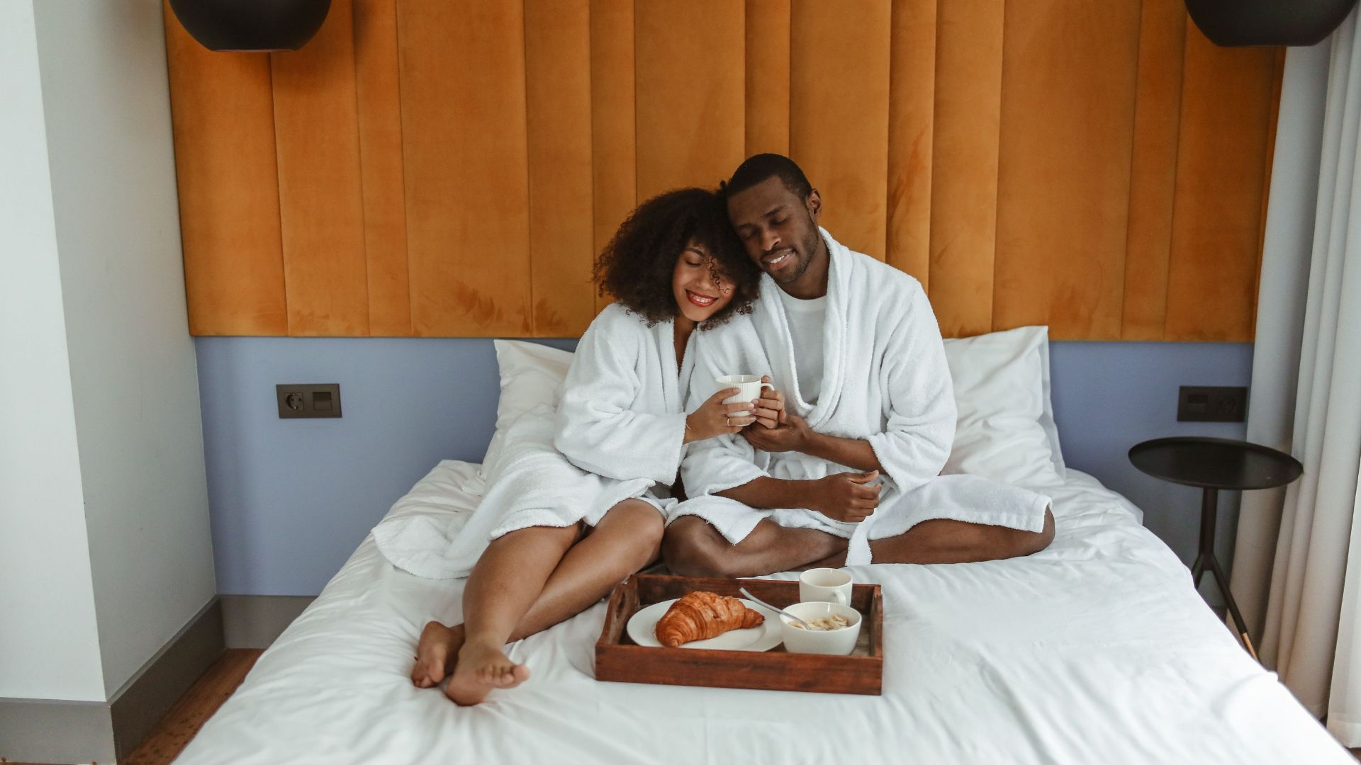 Couple in bathrobes having breakfast in bed, sharing a warm moment. Perfect for lifestyle and relationship themes.