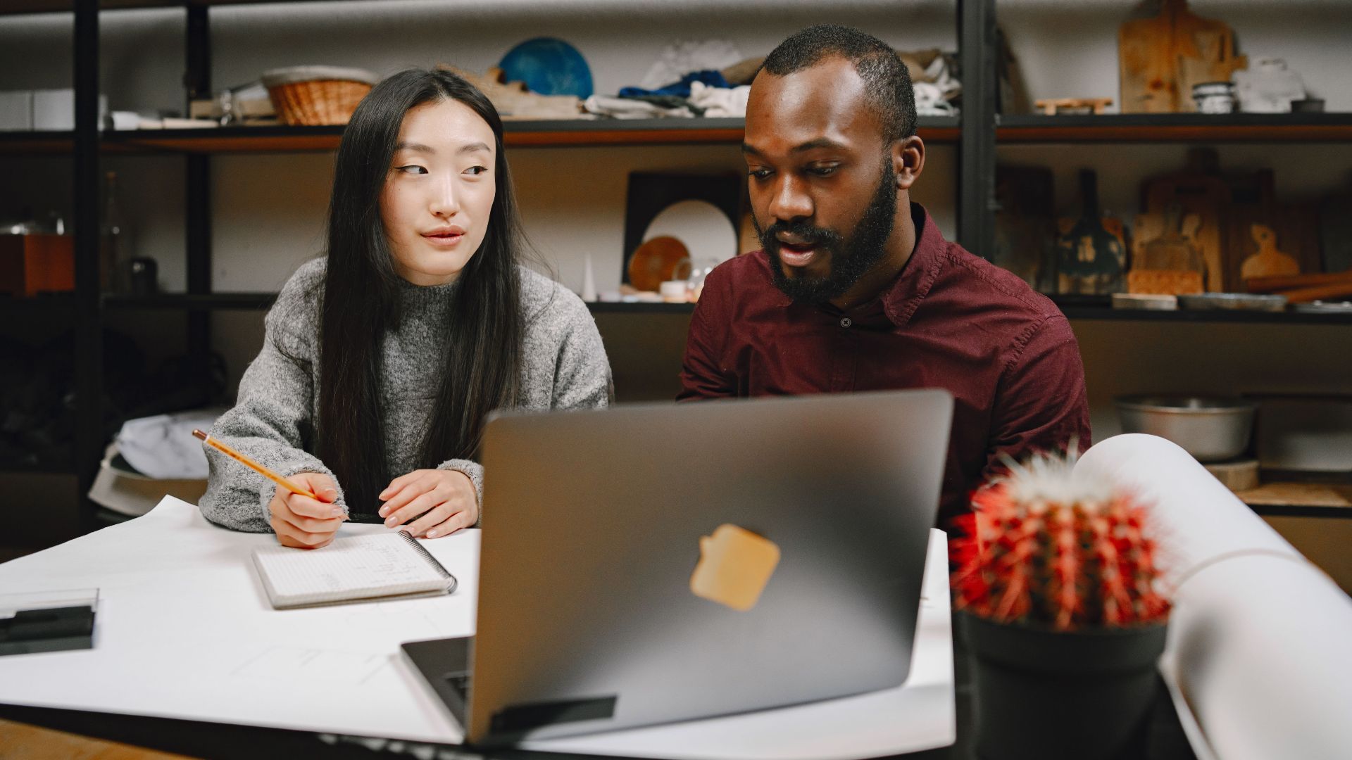 Two colleagues collaborating in a modern workspace with a laptop and notes, fostering creativity and teamwork.