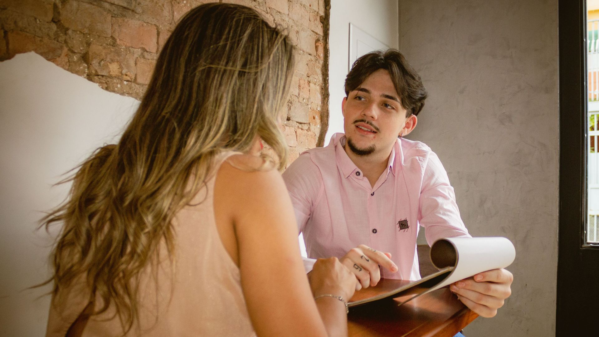 Two adults engaged in a friendly discussion over documents in a cozy café setting.