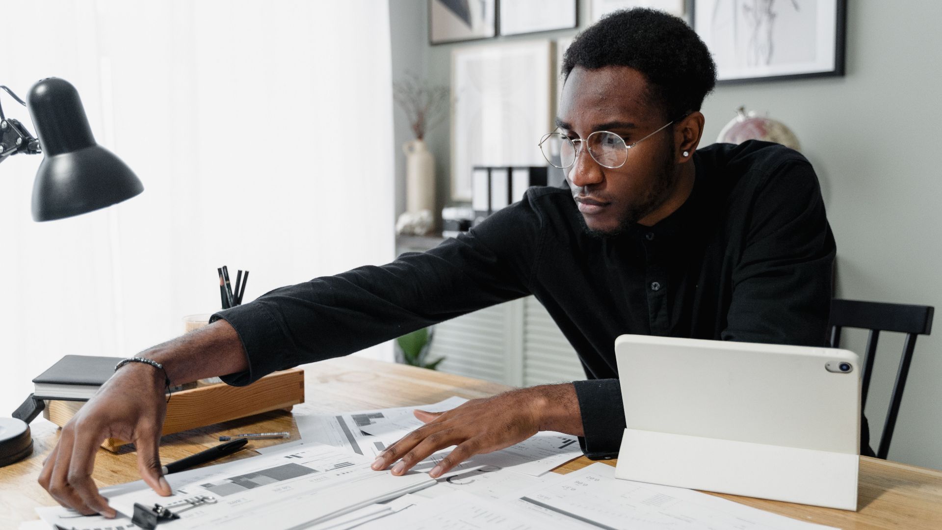 Business professional working at desk reviewing financial documents with digital tablet.