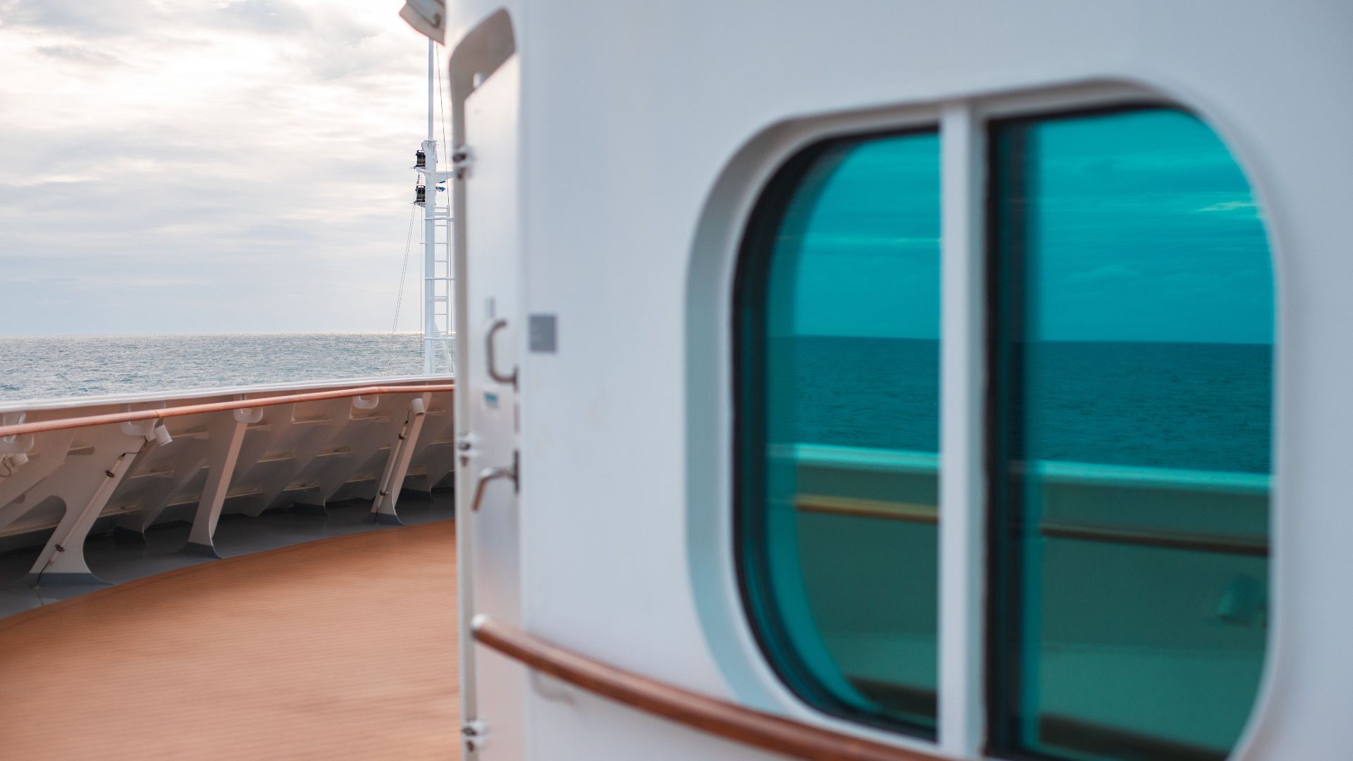 Peaceful view from a cruise ship deck with ocean reflection through a green window.