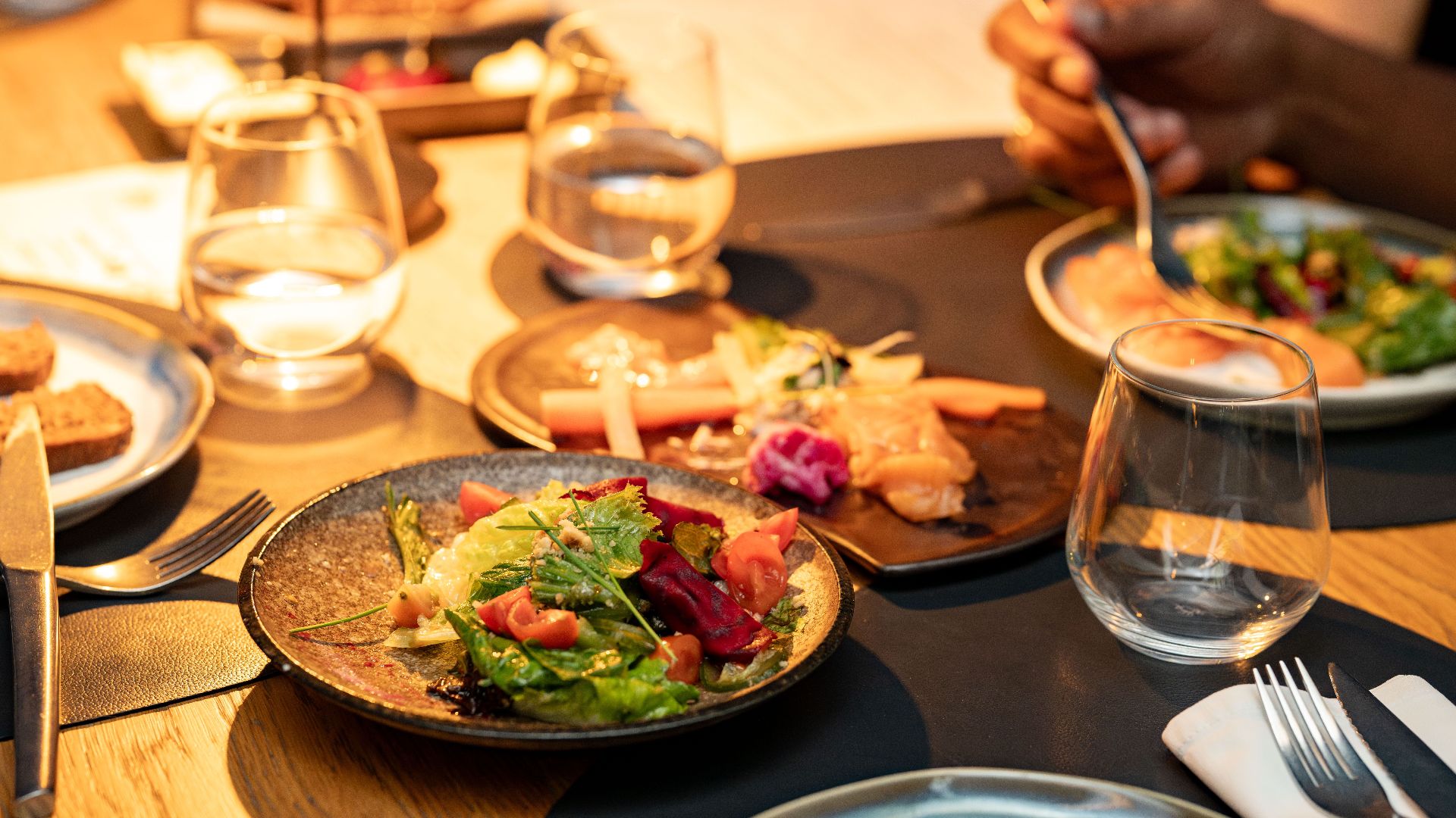 A beautifully set dinner table with gourmet salads and glassware, ideal for a classy dining experience.