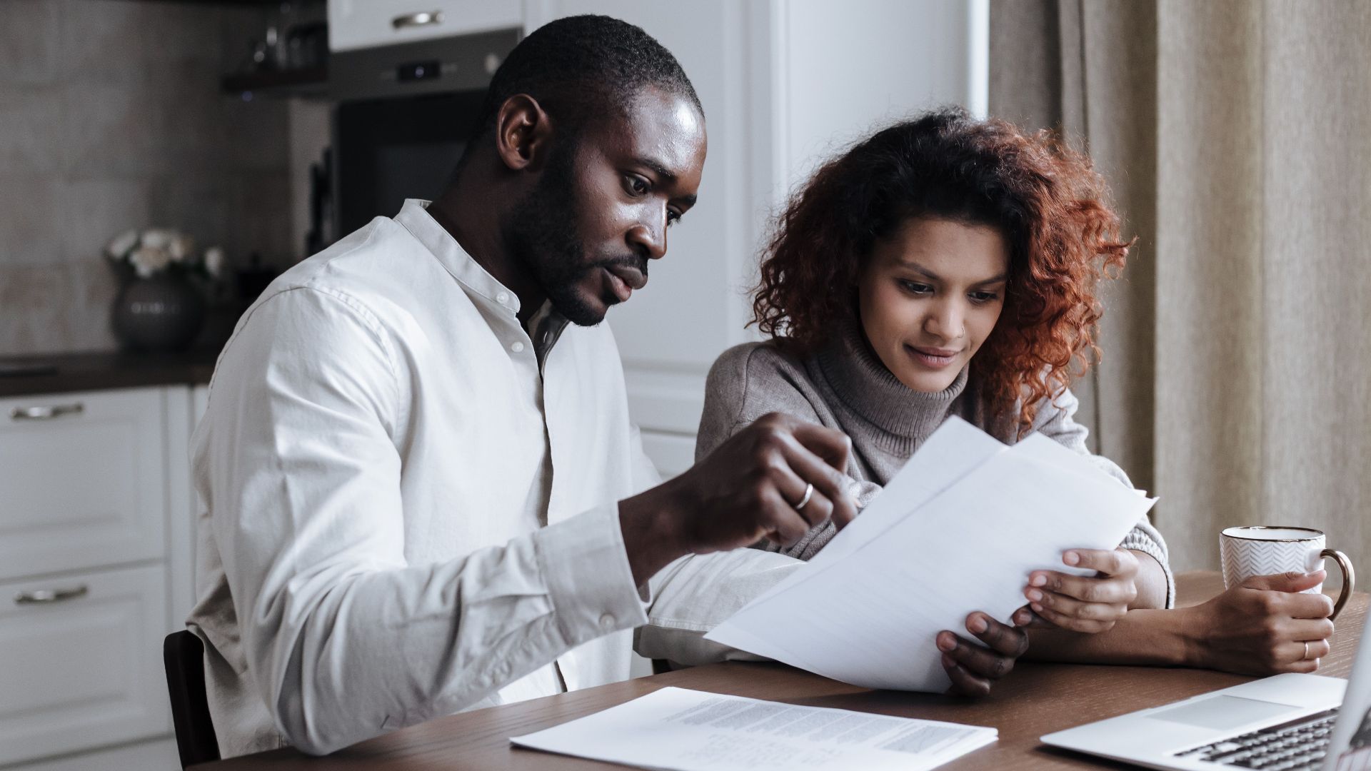 Couple working together on documents at home interior using a laptop.