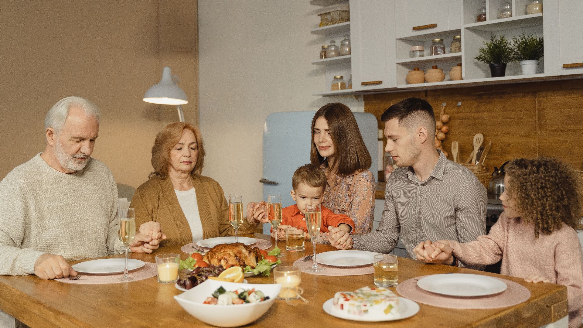 A family gathers for a heartfelt prayer before enjoying a festive meal.
