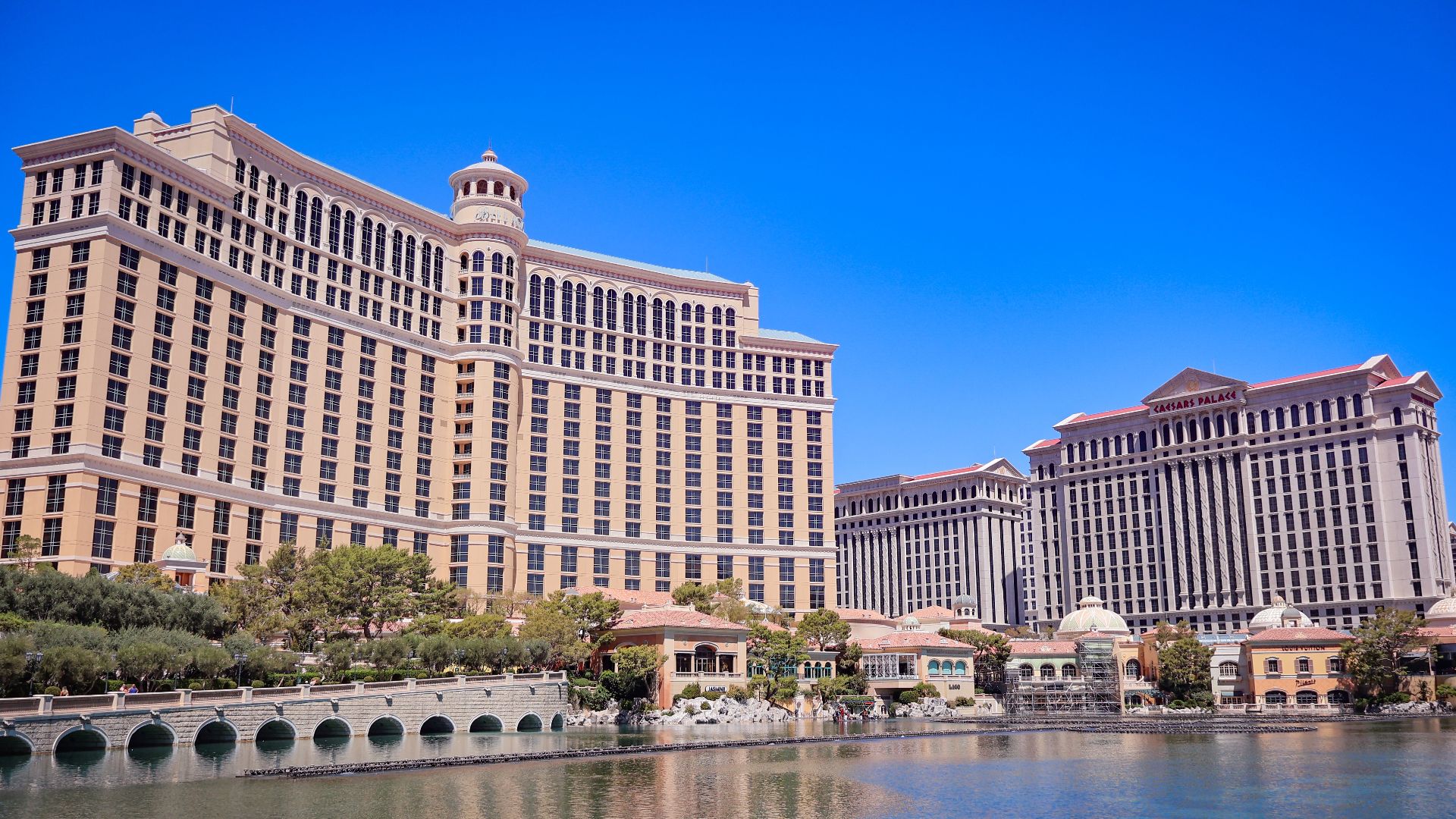 Stunning daylight view of the Bellagio and Caesars Palace in Las Vegas with a clear blue sky and reflective waters.
