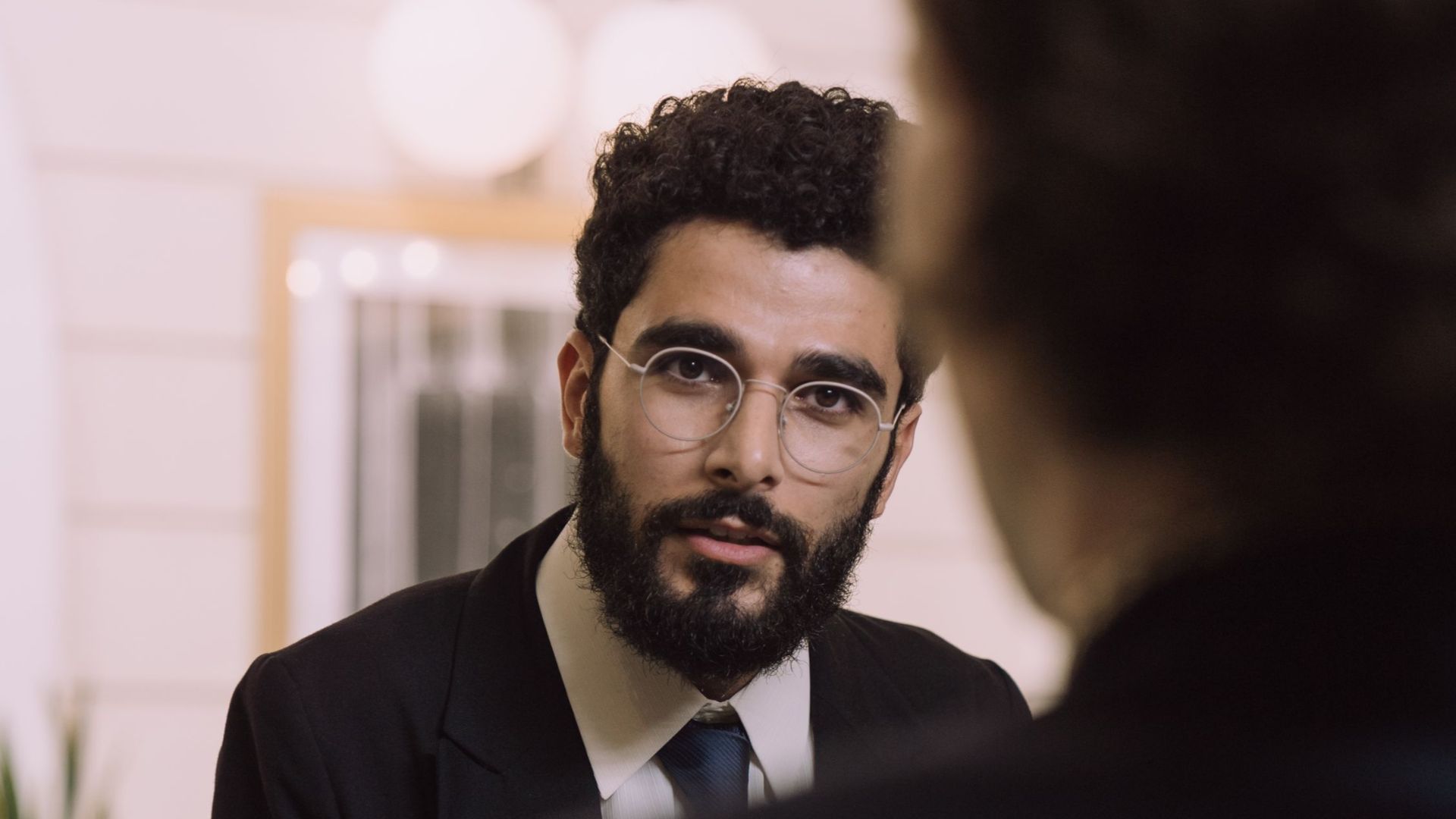A professional businessman checks in at a hotel reception, engaging with a concierge.