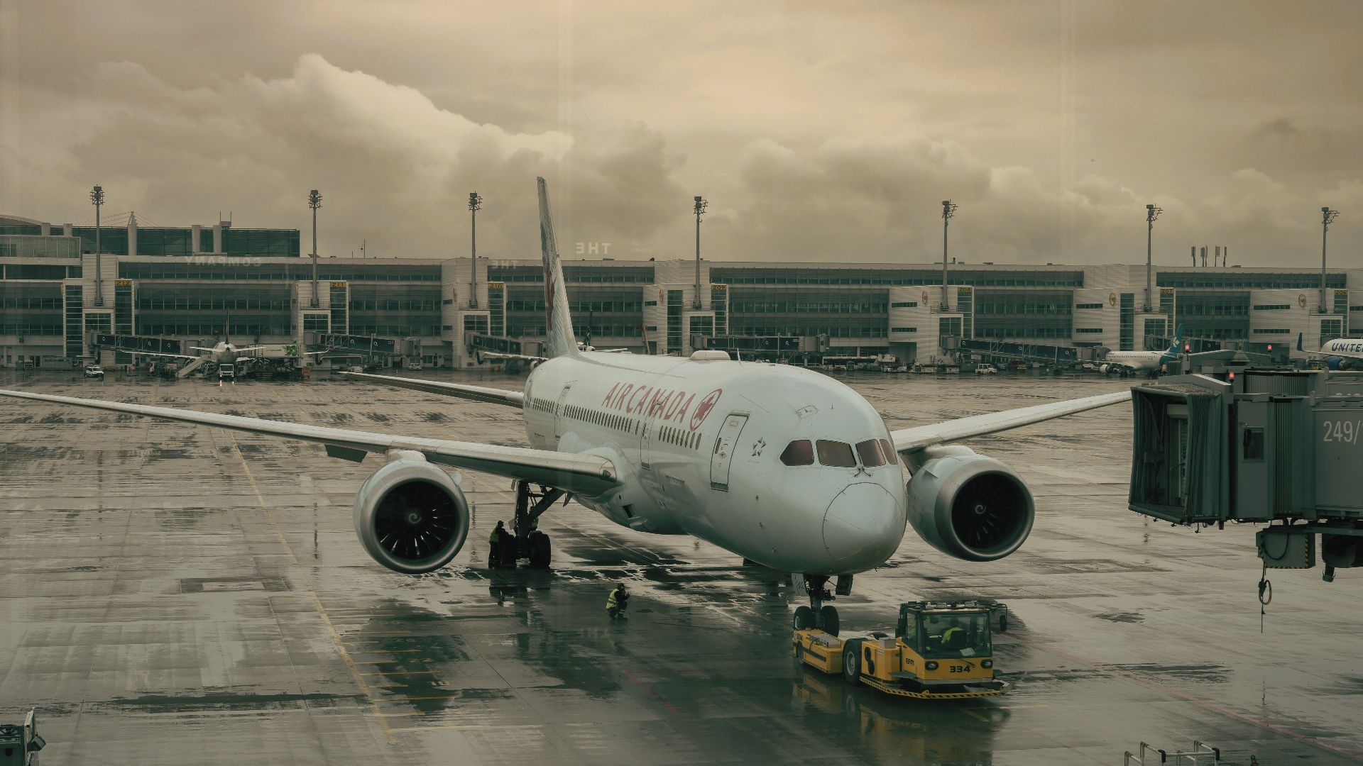 An airplane parked on a wet tarmac at Munich Airport under cloudy skies.