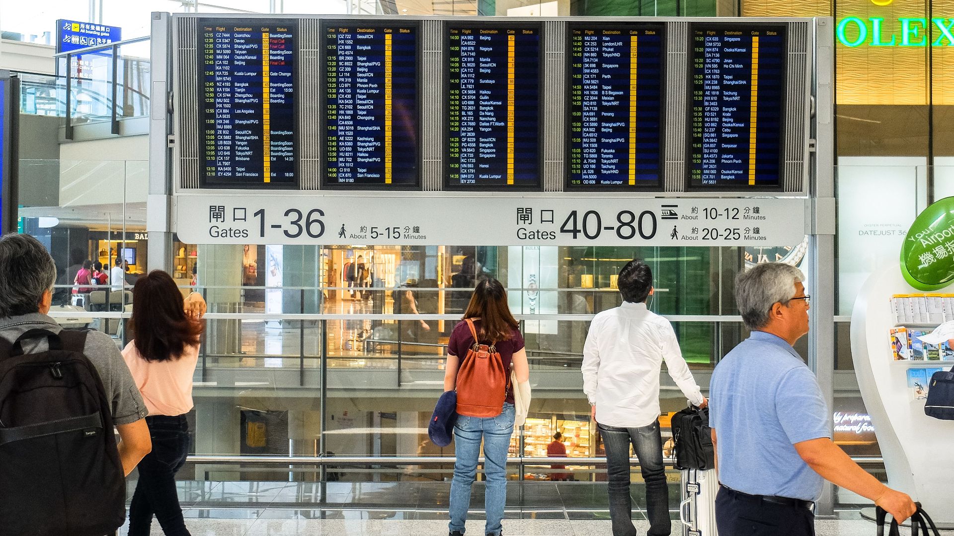 Passengers checking the departure board at Hong Kong International Airport terminal.