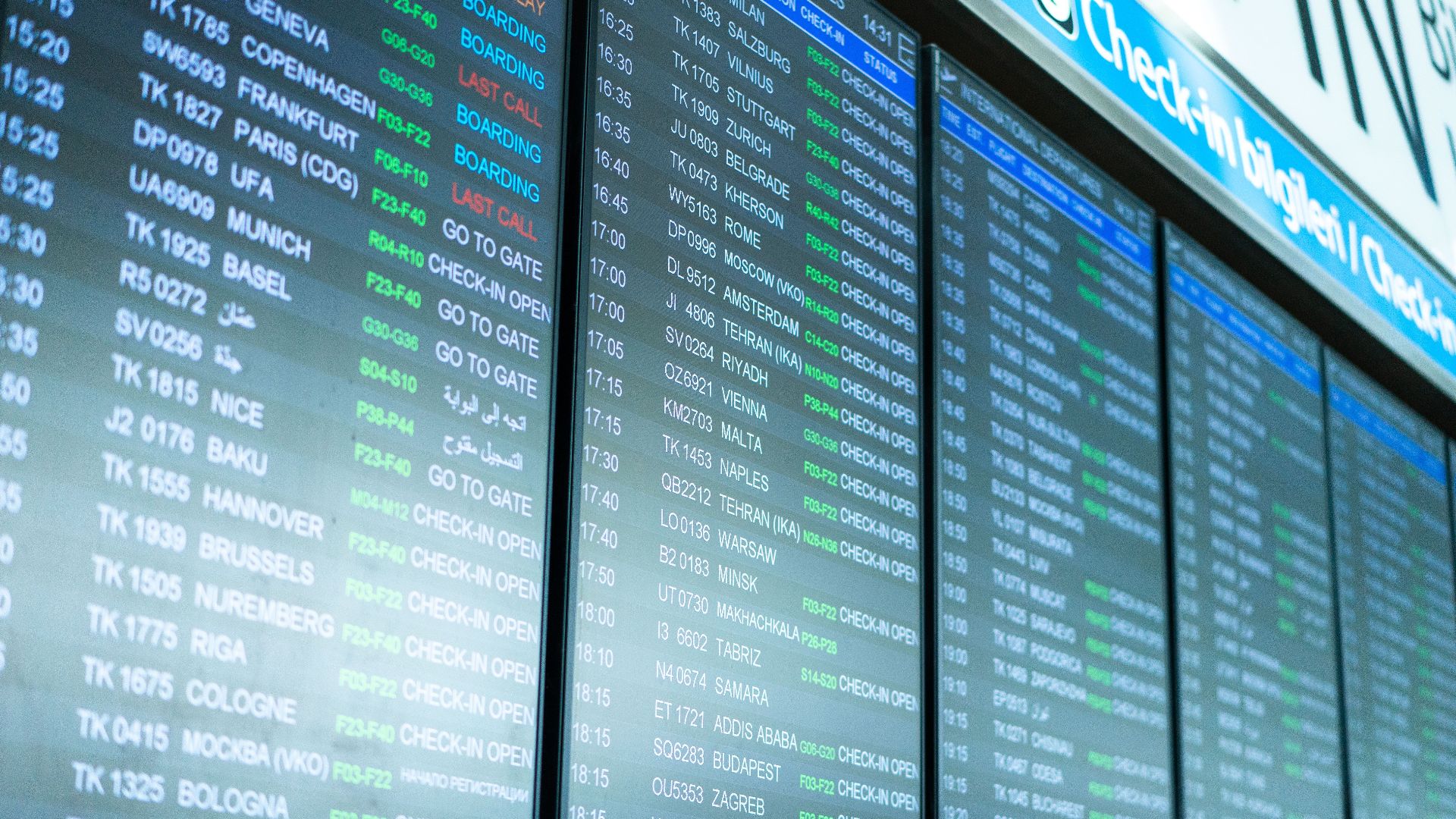Digital screens display flight information and schedules at an airport terminal.
