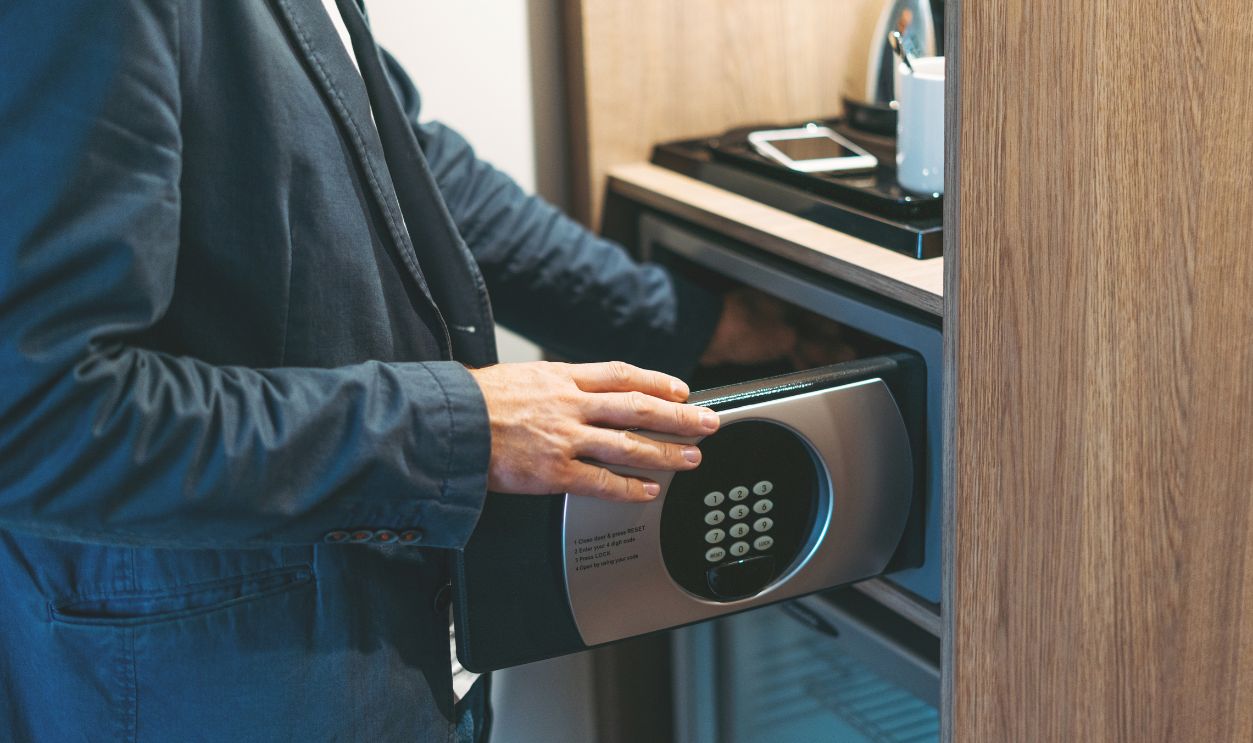 Adult man in blue jacket uses safe in the hotel room