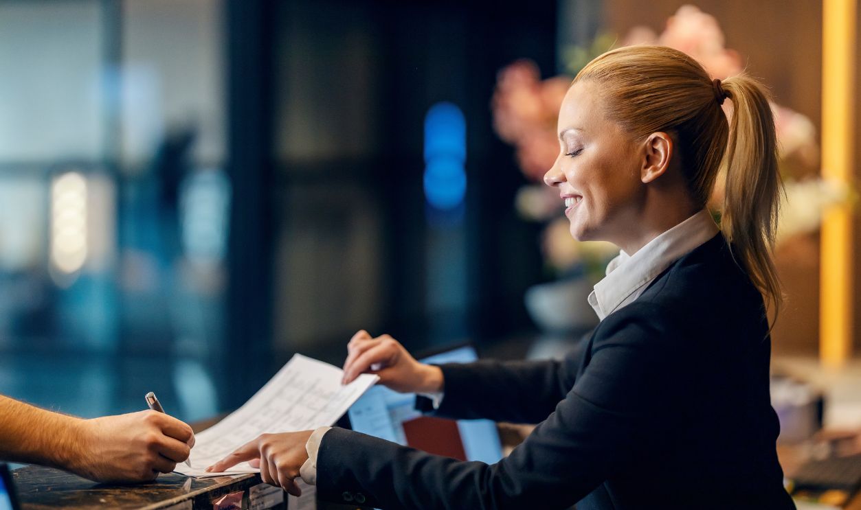 Shutterstock-2231621155, A receptionist is checking in guest in hotel.