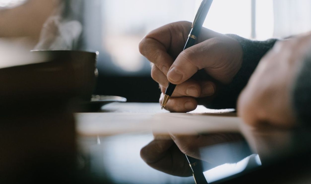Focused adult hand writing with pen in a notebook, capturing creativity and concentration indoors