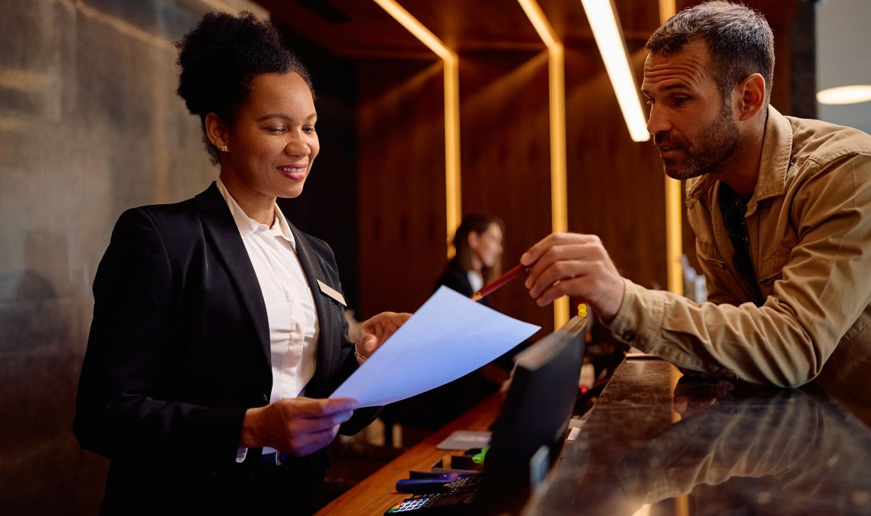 Shutterstock-2601359641, Male guest filling out documents with help of a receptionist while checking in at the hotel.