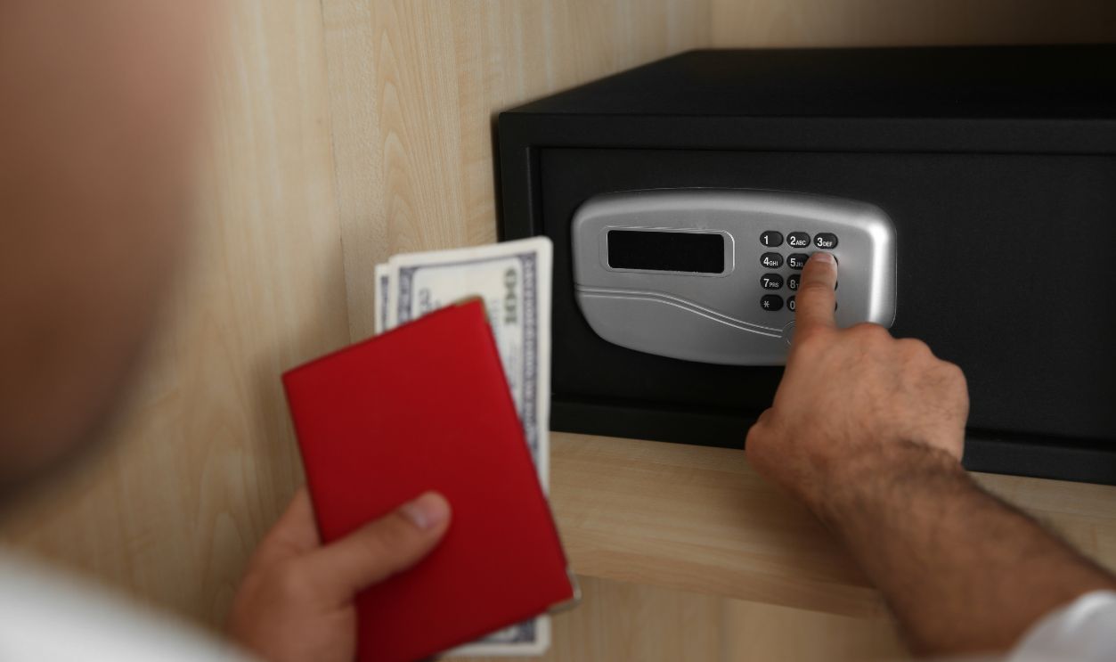 Man opening black steel safe with electronic lock at hotel, closeup