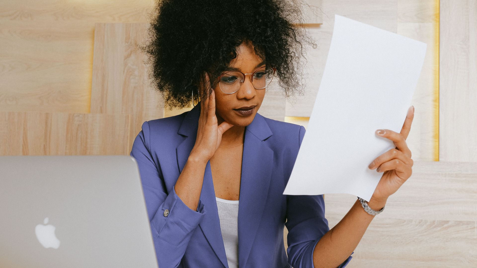 Businesswoman working on a laptop and reviewing a document at the office.