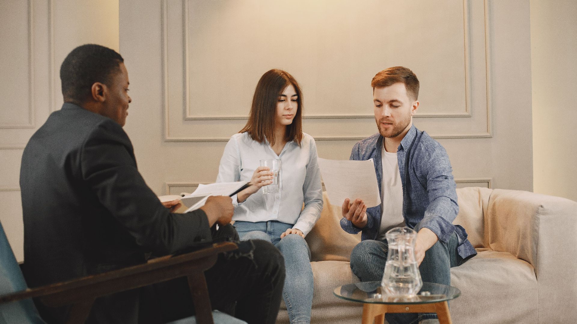 Therapist counseling couple with documents in contemporary office setting.