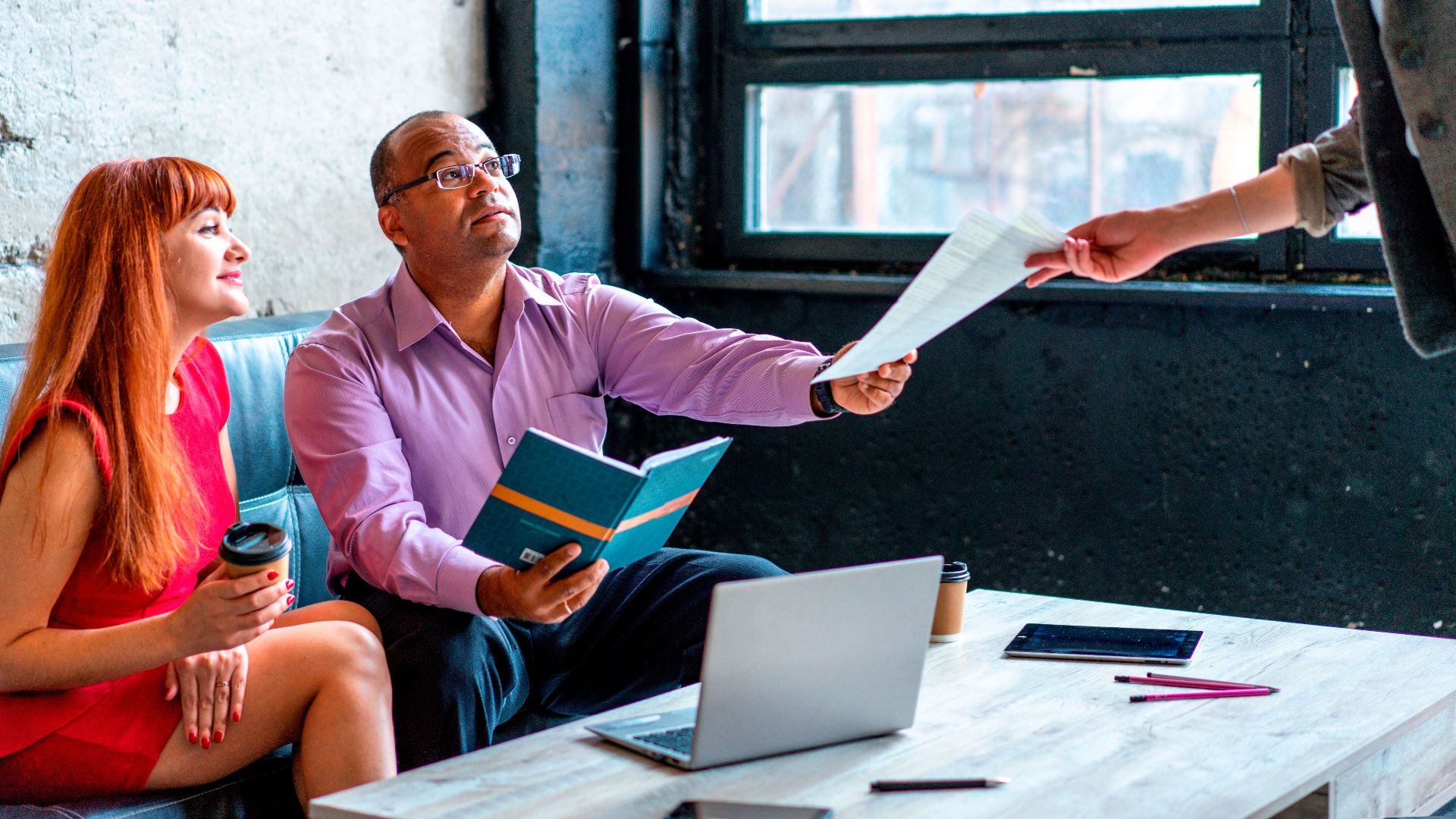 A group of professionals working together in a modern office setting, exchanging documents and ideas.