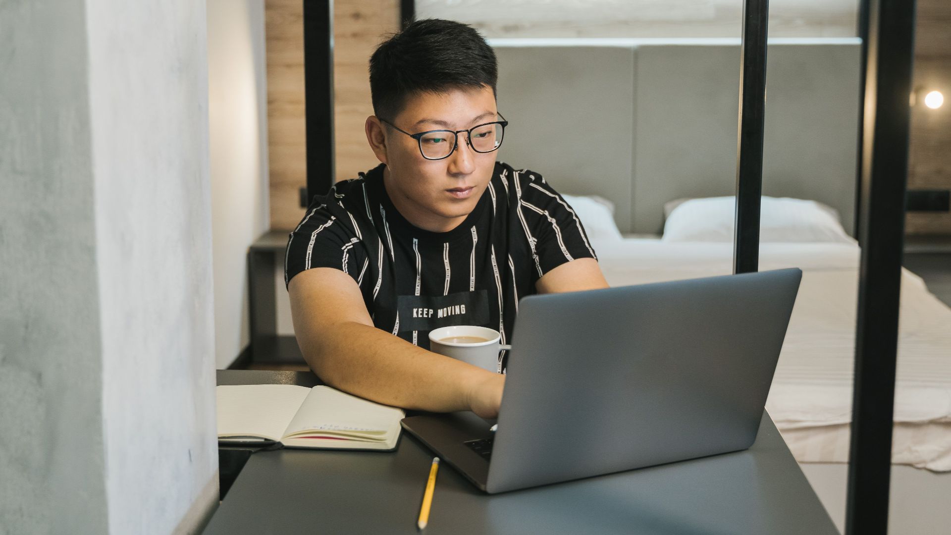 Asian man working on a laptop in a comfortable home office with a modern design.