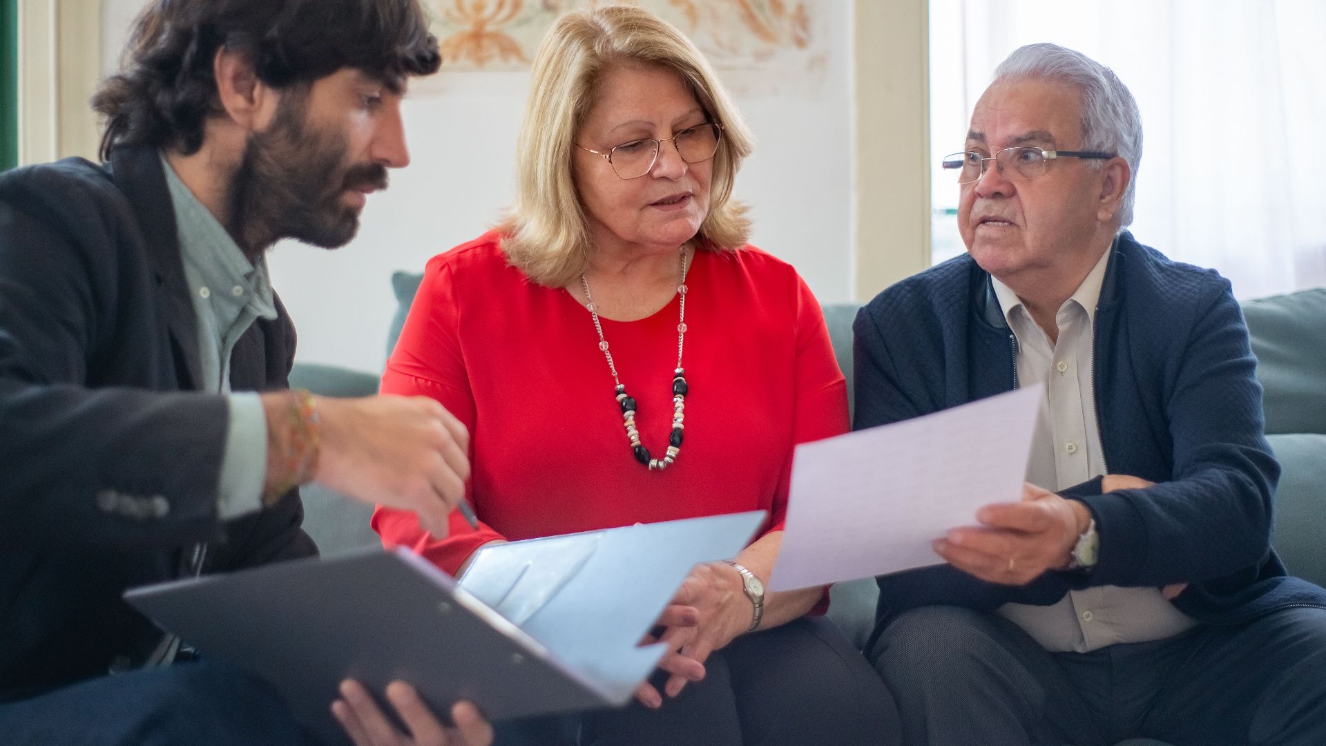 Senior couple consulting with a professional advisor, discussing documents indoors.