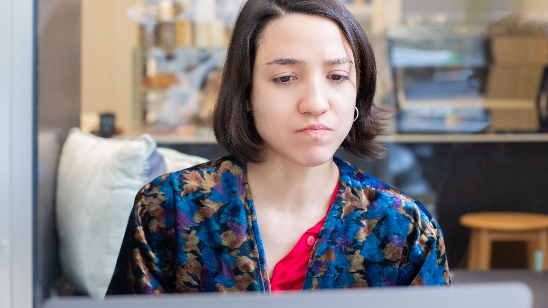 A woman intently working on her laptop in a cafe, captured indoors.