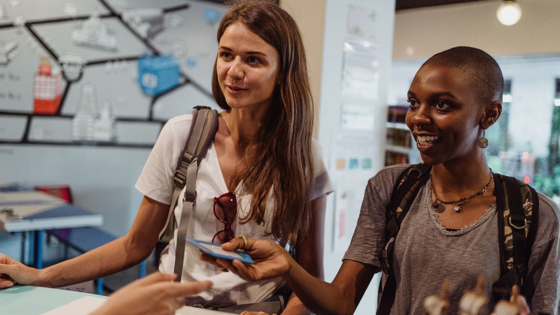 Two women tourists engaging at a hostel reception, offering a friendly atmosphere.