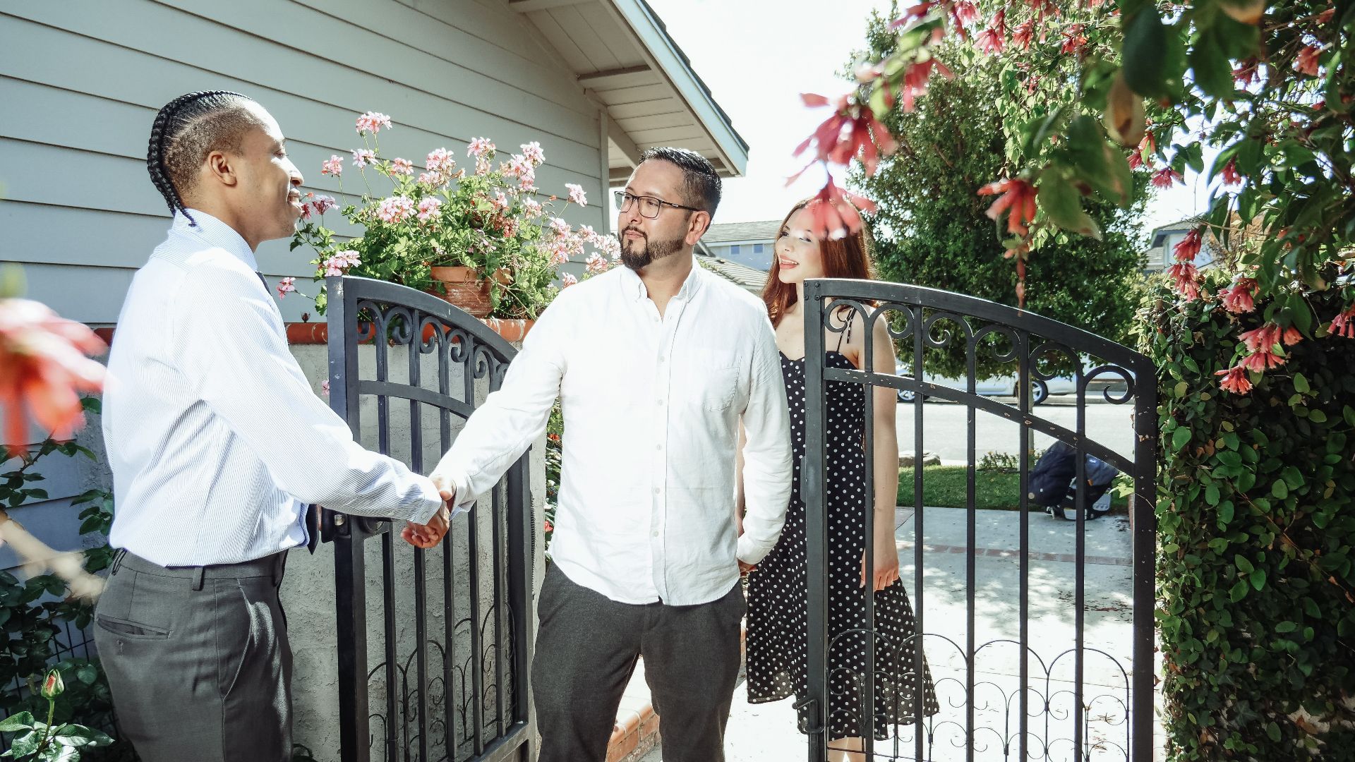A real estate agent meets a couple at their new home, symbolizing a successful property transaction.