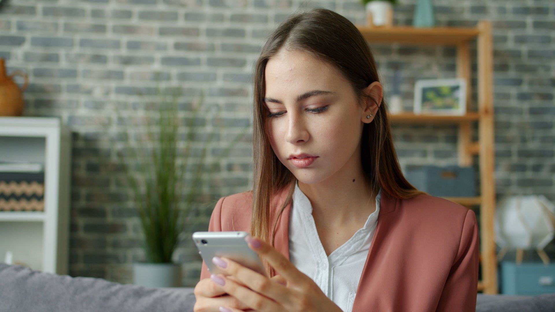 Young woman focused on smartphone in stylish, cozy living room.